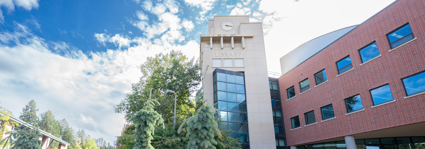 A view of the library clock tower on a warm, partially-cloudy afternoon.