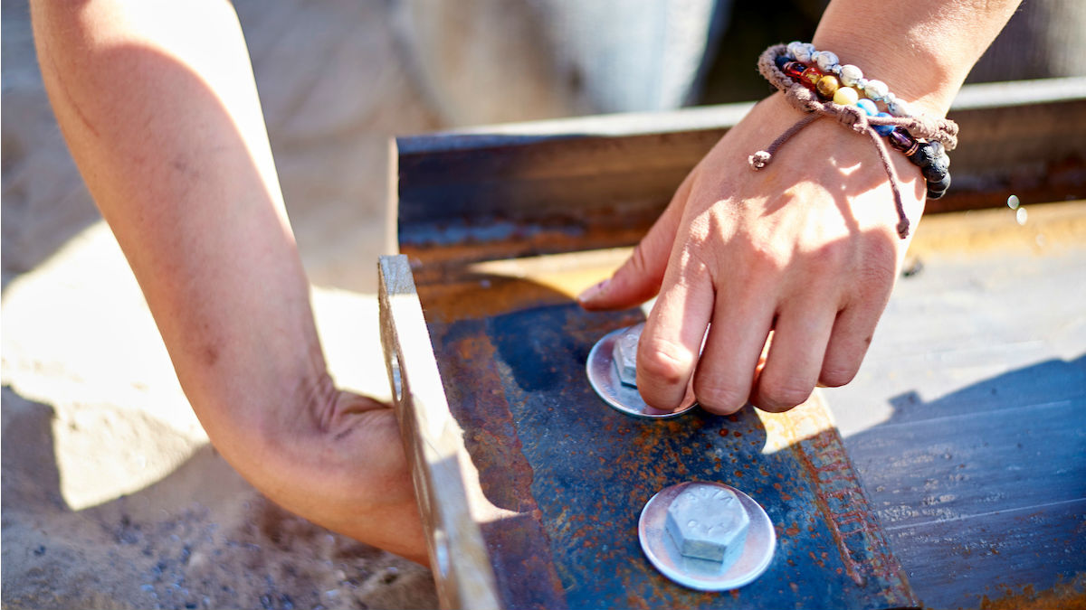 A view of a student's hands tightening a nut.