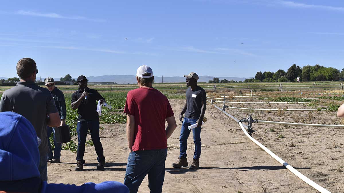 A man speaking to a group of people in a test field.