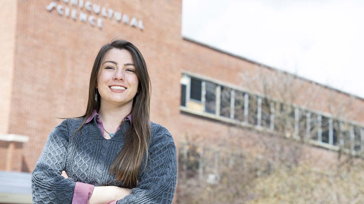 A woman poses outside of a brick building on the University of Idaho campus.