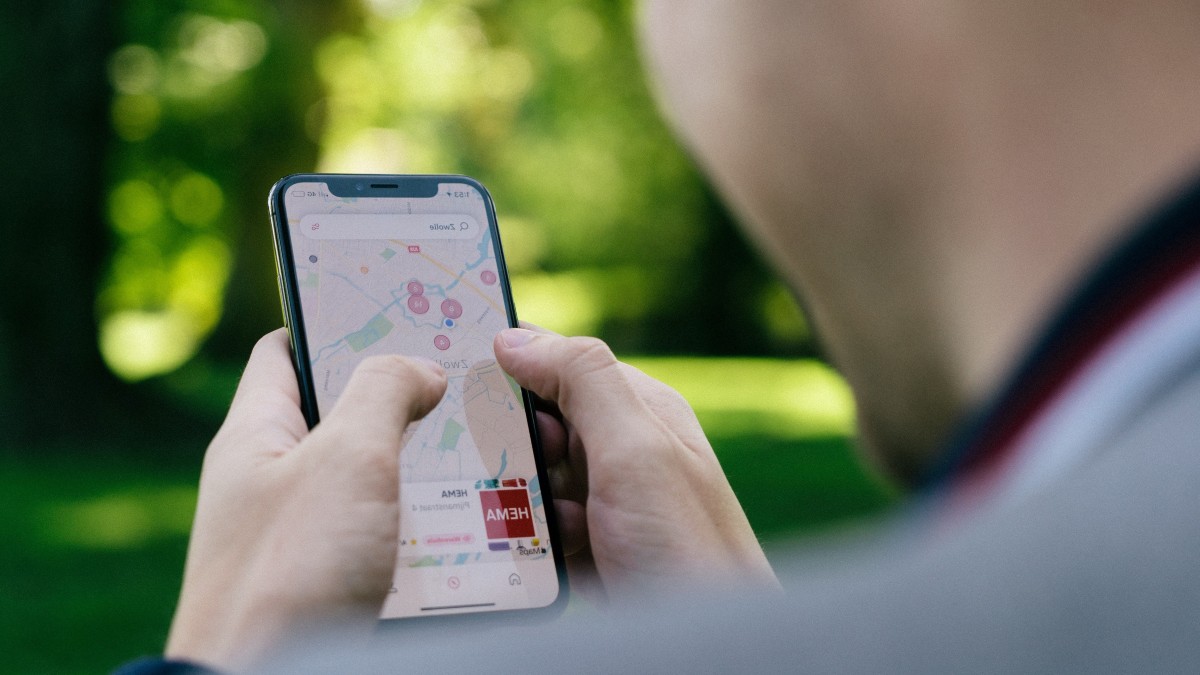 A person holds a smartphone with a map on the screen.