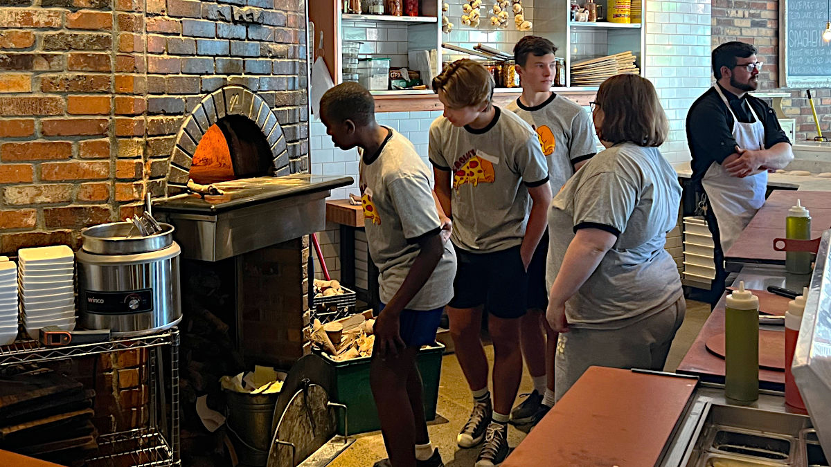 Students in front of pizza oven.