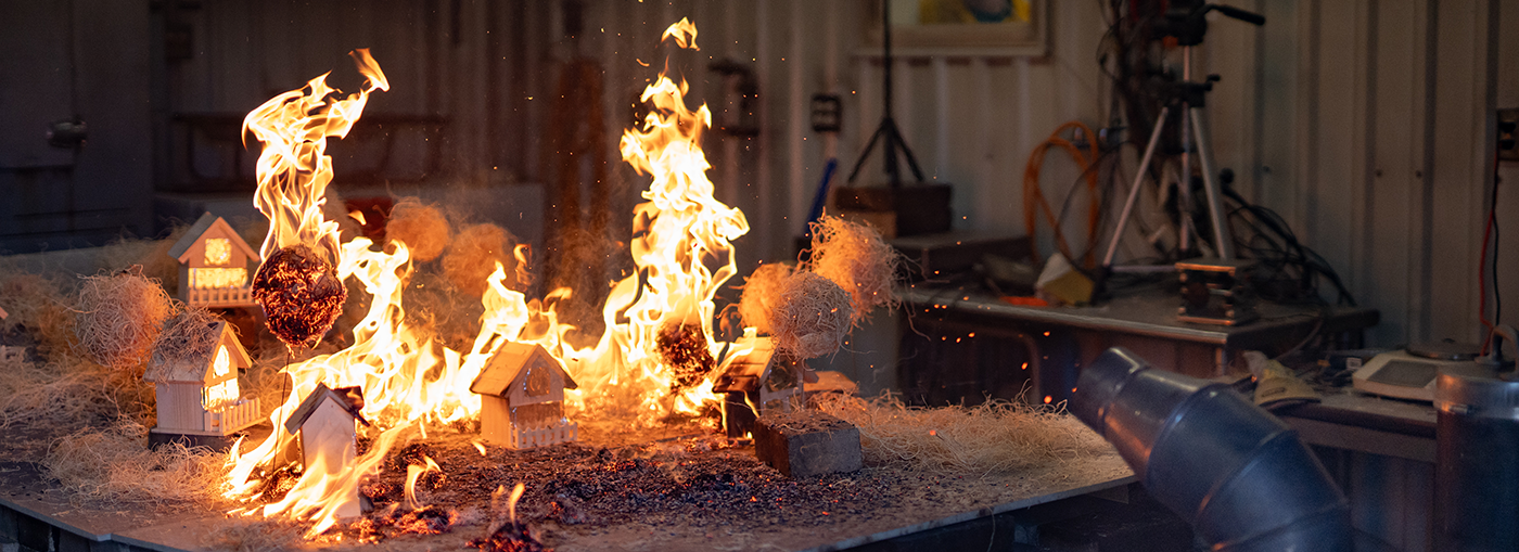 Device used to blow embers across a test area can be seen igniting test area