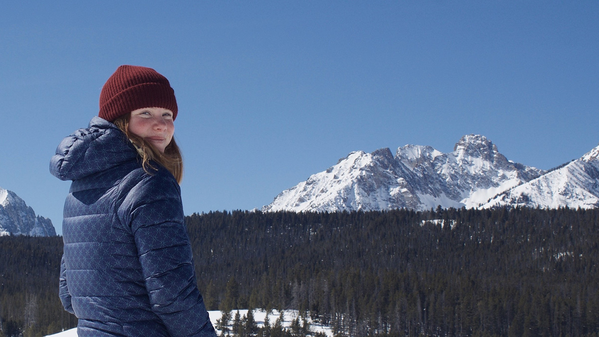 Photo of woman on ski hill with mountain in background.