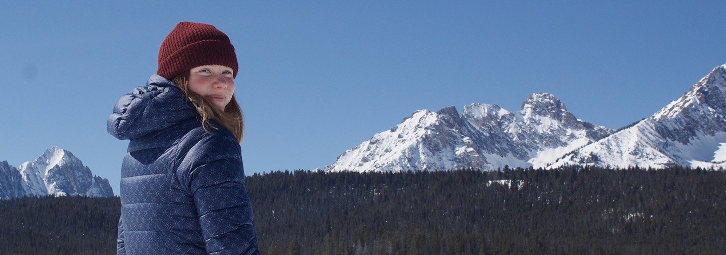 Photo of woman on ski hill with mountain in background.