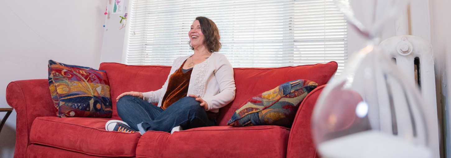 Woman sits on red sofa with legs crossed