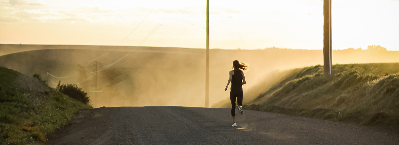 Photo of woman running down a dirt road.