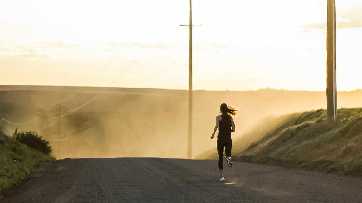 Photo of woman running down a dirt road.