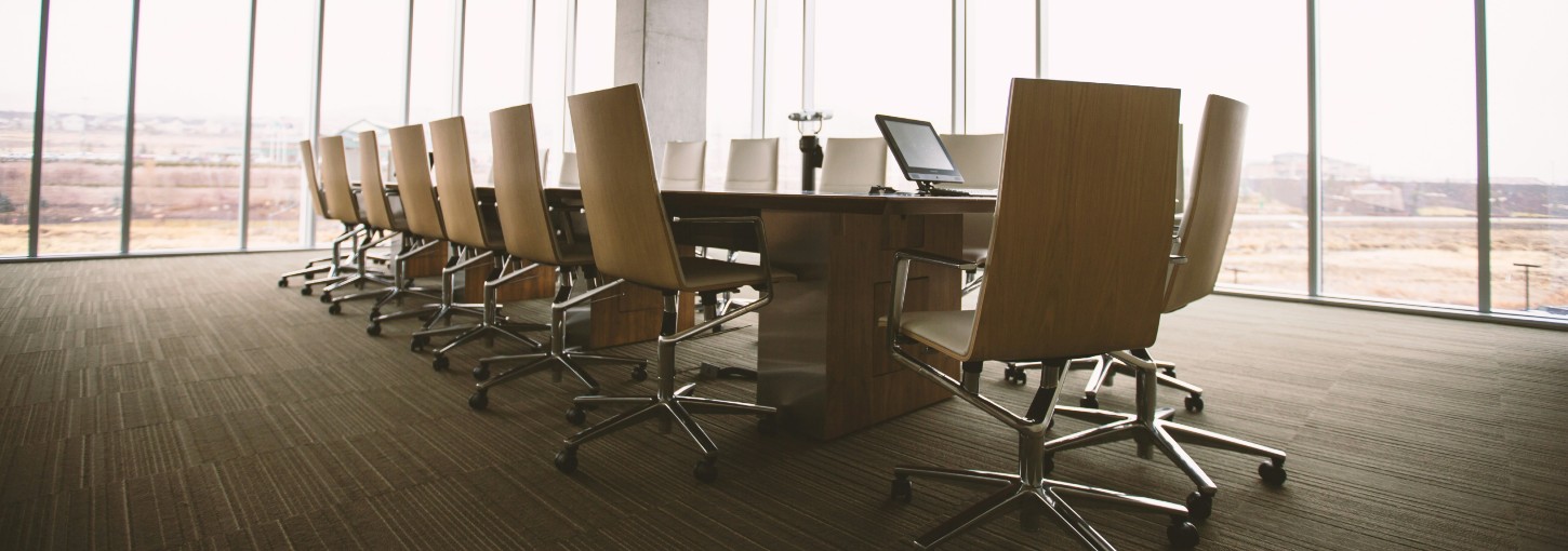 Oval brown wooden conference table and chairs inside conference room