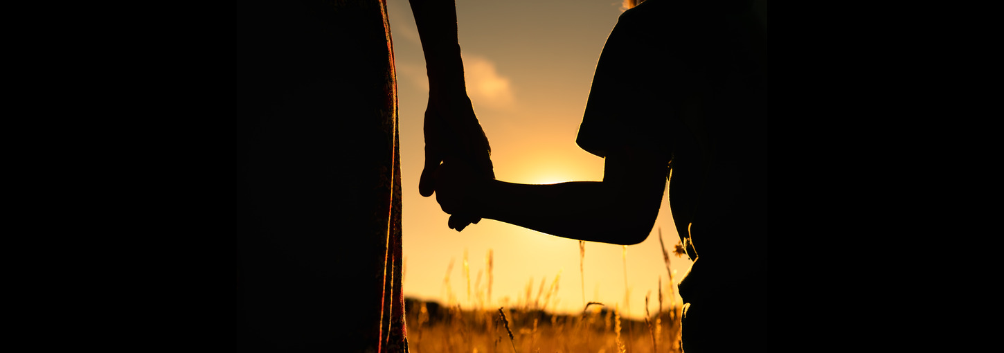 Adult and child holding hands in sunshine