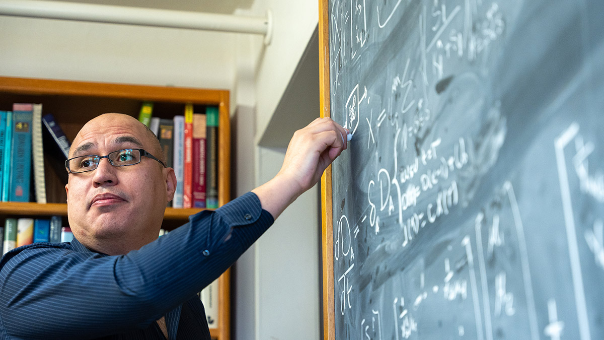 A professor writing on a chalk board